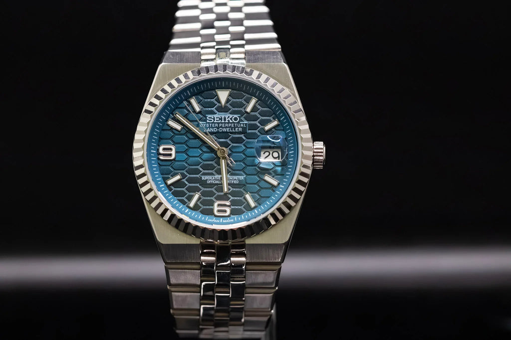 ORA Vanguard 36 deep blue honeycomb dial watch, fluted bezel, jubilee bracelet – front view on reflective surface
