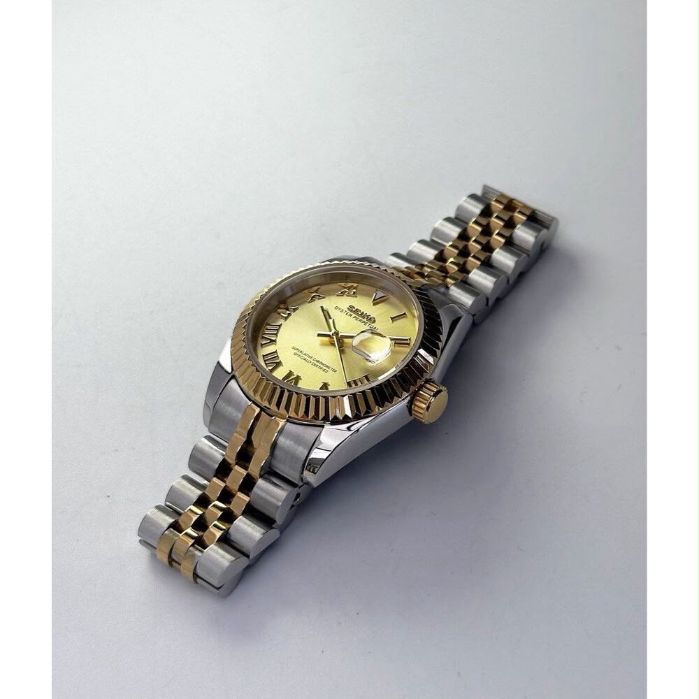 ORA Two-Tone Classic Date ladies Seiko Mod watch lying flat, yellow gold fluted bezel and gold crown, two-tone five-link bracelet – angled view